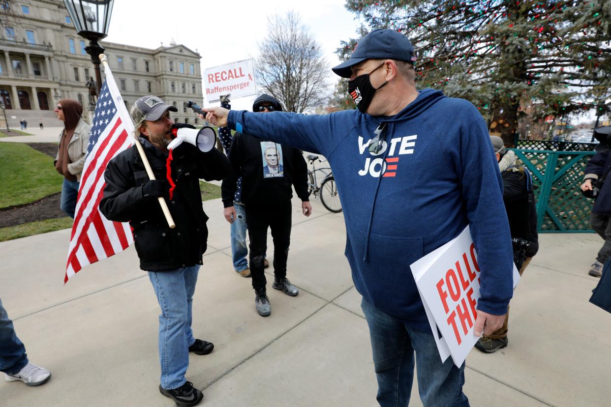 Supporters of US President Donald Trump (L) and a supporter of US President-Elect Joe Biden argue in front of the Michigan State Capital as the Michigan Board of State Canvassers vote today to certify the 2020 election in Lansing, Michigan on November 23, 2020. (Photo by JEFF KOWALSKY / AFP) (Photo by JEFF KOWALSKY/AFP via Getty Images)