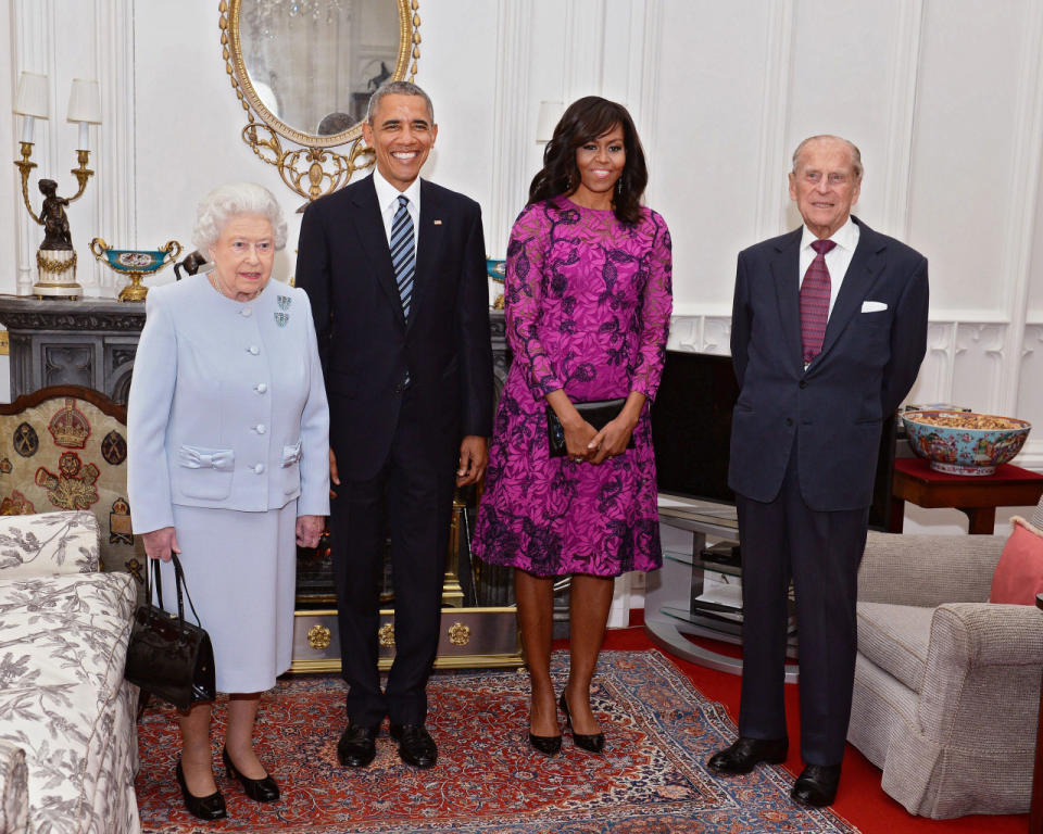 Michelle Obama in a hot pink dress with her beaming husband, President Barack Obama, Queen Elizabeth II, and Prince Phillip.