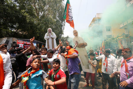 Supporters of India's ruling Bharatiya Janata Party (BJP) celebrate as they carry cut-outs of their party's President Amit Shah and India's Prime Minister Narendra Modi after learning of the initial poll results of Karnataka state assembly elections, in Bengaluru, India, May 15, 2018. REUTERS/Abhishek N. Chinnappa