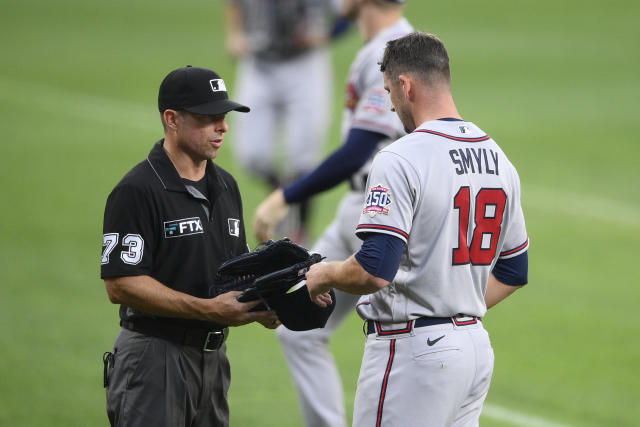 Third base umpire Tripp Gibson (73) inspects the hat and glove of Atlanta Braves starting pitcher Drew Smyly (18) after the first inning of a baseball game against the Baltimore Orioles, Saturday, Aug. 21, 2021, in Baltimore. (AP Photo/Nick Wass)