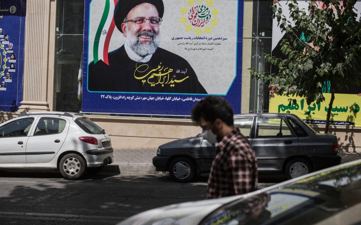 A man walks by a campaign office of Ebrahim Raisi who today was named as the winner of the Iranian Presidential Election, in Tehran - Sam Tarling/Sam Tarling for The Telegraph