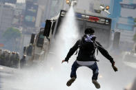 <p>A demonstrator jumps away from a jet of water from a riot security forces vehicle during a rally against Venezuela’s President Nicolas Maduro in Caracas, Venezuela, May 26, 2017. (Carlos Barria/Reuters) </p>