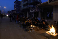 People warm up with fire next to destroyed buildings in Antakya, southern Turkey, Thursday, Feb. 9, 2023. Tens of thousands of people who lost their homes in a catastrophic earthquake huddled around campfires in the bitter cold and clamored for food and water Thursday, three days after the temblor hit Turkey and Syria. (AP Photo/Khalil Hamra)