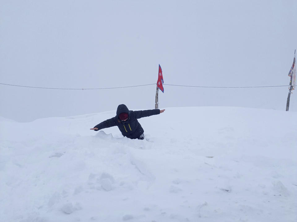 In this Friday, Jan. 17, 2020 photo, a trekker wades through piles of snow before being rescued on the day after an avalanche hit Mount Annapurna trail in Nepal. Special army and government rescue personnel were searching again on Monday for four South Korean trekkers and their three Nepali guides lost since an avalanche swept a popular trekking route in Nepal's mountains. (AP Photo/Phurba Ongel Sherpa)