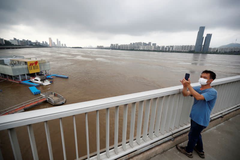 A man takes photographs of flooded Han River in Seoul