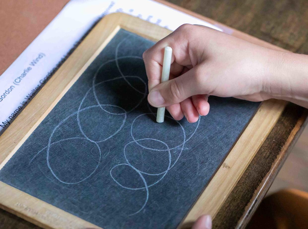 A Rosarian Academy fourth grade student practices writing the way children would have in the late 1800s during a field trip to the Little Red Schoolhouse in Palm Beach Wednesday, March 6, 2024.