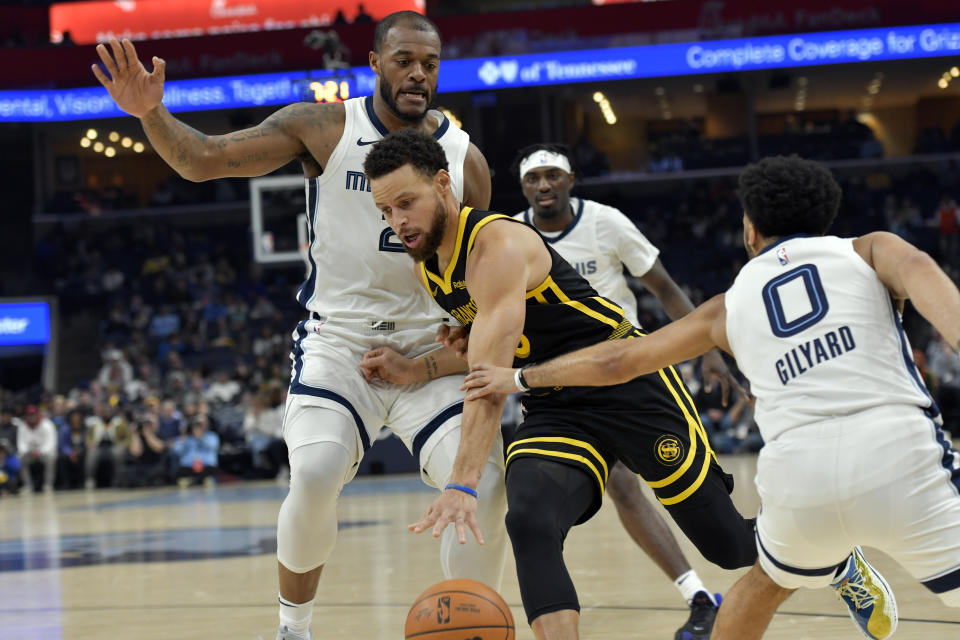 Golden State Warriors guard Stephen Curry, center, drives between Memphis Grizzlies forward Xavier Tillman (2) and guard Jacob Gilyard (0) in the first half of an NBA basketball game Monday, Jan. 15, 2024, in Memphis, Tenn. (AP Photo/Brandon Dill)