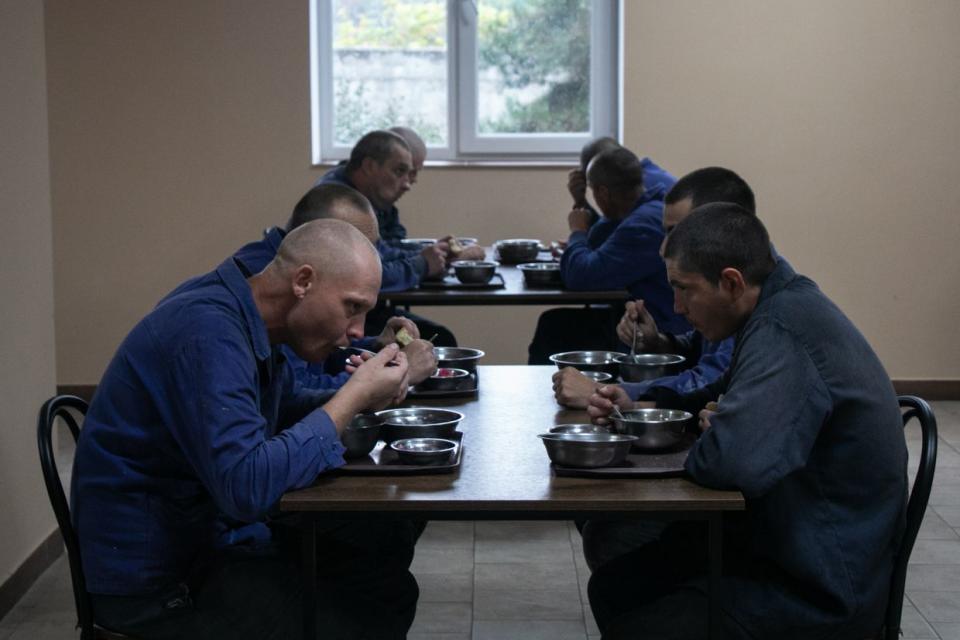 Russian prisoners of war having lunch inside a POW camp in Ukraine in Sept., 2023. The lunch includes a vegetable salad, a thin pea and potato soup, porridge with butter, a meat patty, and freshly baked bread. (Alexander Khrebet / The Kyiv Independent)