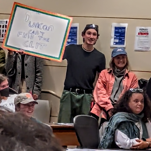 “Duncan can’t find the clit,” reads a sign held by one of the protesters who shouted down Judge Stuart Duncan at Stanford Law School, where he had been invited to speak. Seated bottom right is Tirien Steinbach, Stanford’s Associate Dean for Diversity, Equity, and Inclusion. (Screenshot of footage by Aaron Sibarium)