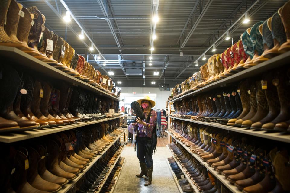 Store manager Bridgette Detienne grabs a boot off a shelf at Boot Barn, located at 112 Walker Springs Road in West Knoxville, Friday, May 21, 2021. Boot Barn, which operates over 250 locations in 30 states, opened its newest Knoxville location in March. 