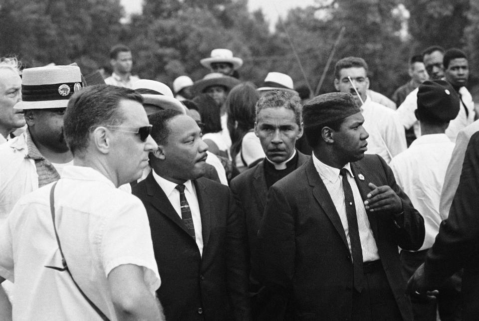 The Rev. Martin Luther King has his attention drawn to a sign, displayed by jeering white youths, as they marched into all-white neighborhood on far Southwest Side of city in Chicago, Aug. 22, 1966.