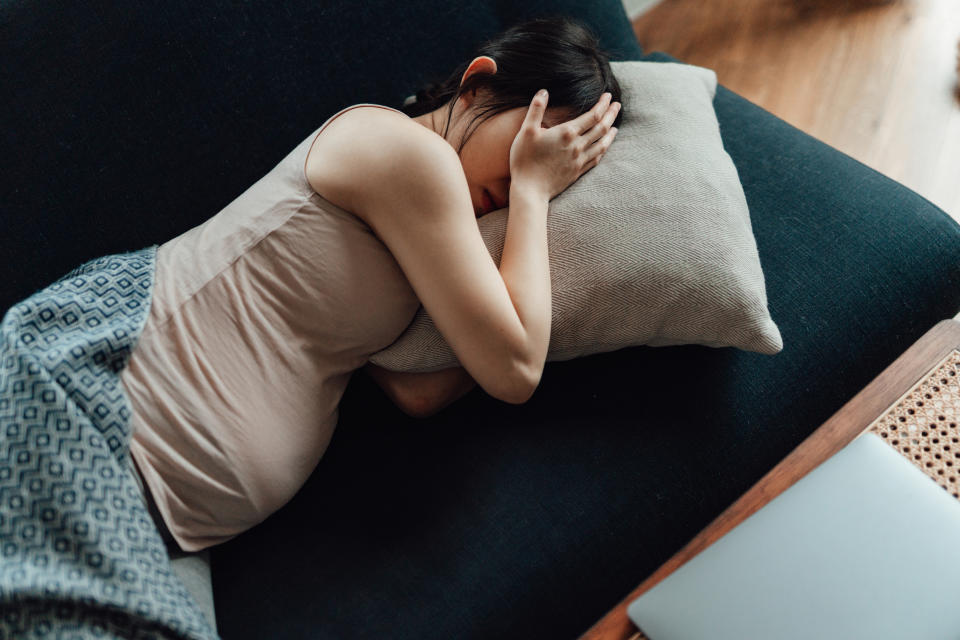 a pregnant person lying on the couch sad