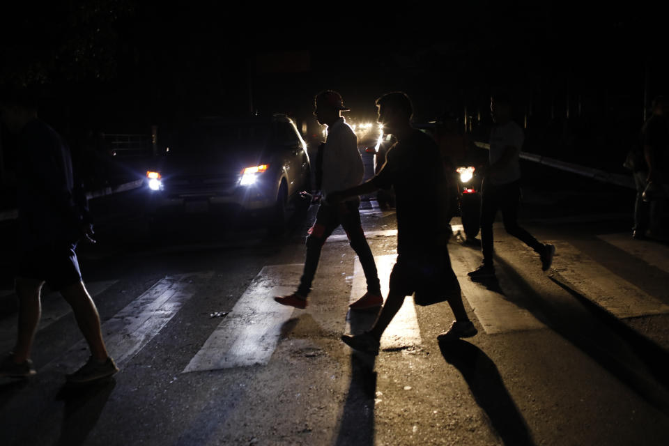 FILE - In this Monday, July 22, 2019, file photo, people walk on a street during a blackout in Caracas, Venezuela. When much of Venezuela was plunged into darkness after a massive blackout earlier in the week, Maduro blamed the power outage on an “electromagnetic attack” carried out by the United States. (AP Photo/Ariana Cubillos, File)