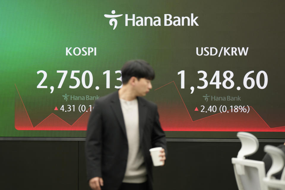 A currency trader walks by the screens showing the Korea Composite Stock Price Index (KOSPI), left, and the foreign exchange rate between U.S. dollar and South Korean won at a foreign exchange dealing room in Seoul, South Korea, Friday, March 29, 2024. Asian shares were mostly higher Friday in quiet holiday trading, with markets closed in Hong Kong, Sydney, Singapore and India, among other places. (AP Photo/Lee Jin-man)