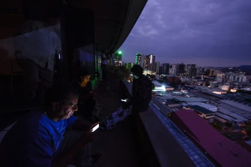 Journalists use cell phones during a huge blackout in Venezuela