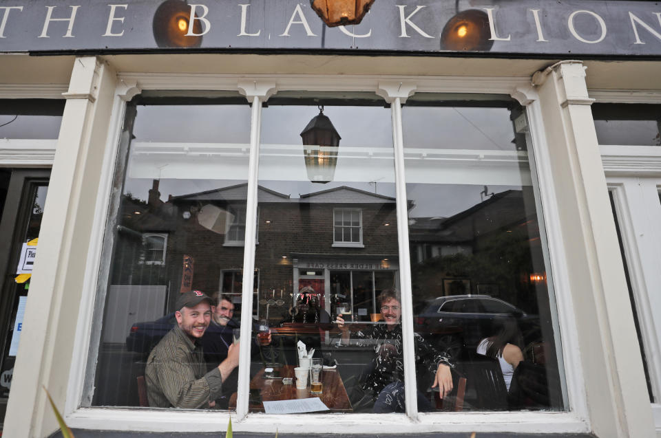 People enjoy their drinks at The Black Lion pub in London, Saturday, July 4, 2020. England is embarking on perhaps its biggest lockdown easing yet as pubs and restaurants have the right to reopen for the first time in more than three months. In addition to the reopening of much of the hospitality sector, couples can tie the knot once again, while many of those who have had enough of their lockdown hair can finally get a trim. (AP Photo/Frank Augstein)