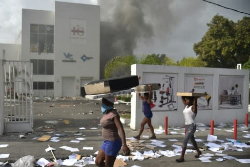 People carry loot from a shop in the commune of Petionville during protests against an increase in fuel prices, which the government has suspended