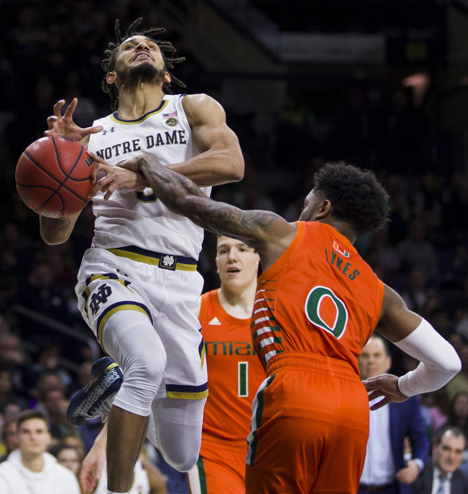 Notre Dame's Prentiss Hubb, left, gets fouled under the basket by Miami's Chris Lykes (0) during the second half of an NCAA college basketball game Sunday, Feb. 23, 2020, in South Bend, Ind. (AP Photo/Robert Franklin)