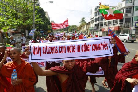 A Buddhist monk holds up a banner during a protest to demand the revocation of the right of holders of temporary identification cards, known as white cards, to vote, in Yangon February 11, 2015. REUTERS/Soe Zeya Tun