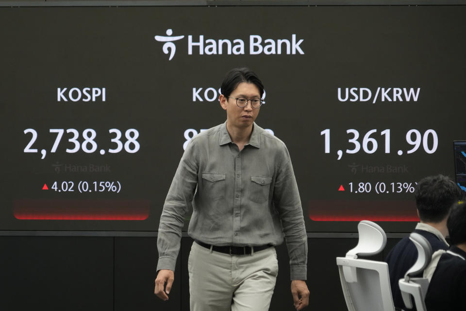 A currency trader passes by the screen showing the Korea Composite Stock Price Index (KOSPI), left, and the foreign exchange rate between U.S. dollar and South Korean won, right, at the foreign exchange dealing room of the KEB Hana Bank headquarters in Seoul, South Korea, Wednesday, May 8, 2024. (AP Photo/Ahn Young-joon)