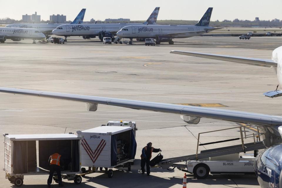 PHOTO: Workers unload luggage from a JetBlue plane at Terminal 4 at John F. Kennedy International Airport, Nov. 24, 2021, in New York. (Angus Mordant/Bloomberg via Getty Images, FILE)