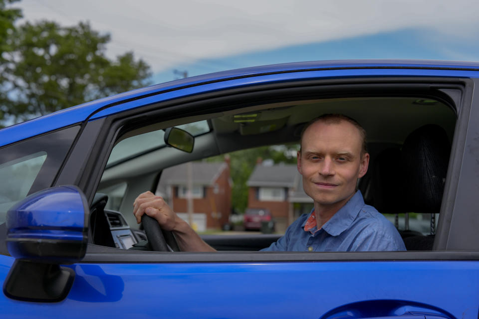 Caleb Jud, 33, poses for a portrait in his Honda Fit, Monday, May 13, 2024, in Cincinnati. (Many Americans still aren’t sold on going electric for their next car purchase. High prices and a lack of easy-to-find charging stations are major sticking points, a new poll shows. Jud said he’s considering an EV, but may end up with a plug-in hybrid — if he goes electric. AP Photo/Joshua A. Bickel)