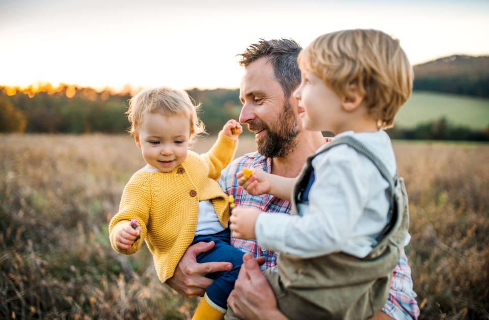 Dad holding two toddlers while outdoors