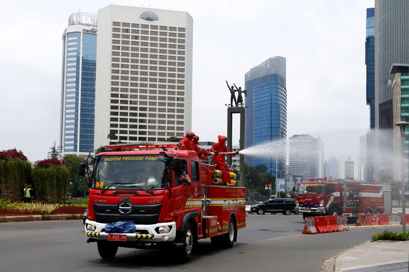 Firefighters spray disinfectant on the road, to prevent the spread of coronavirus disease (COVID-19) in Jakarta