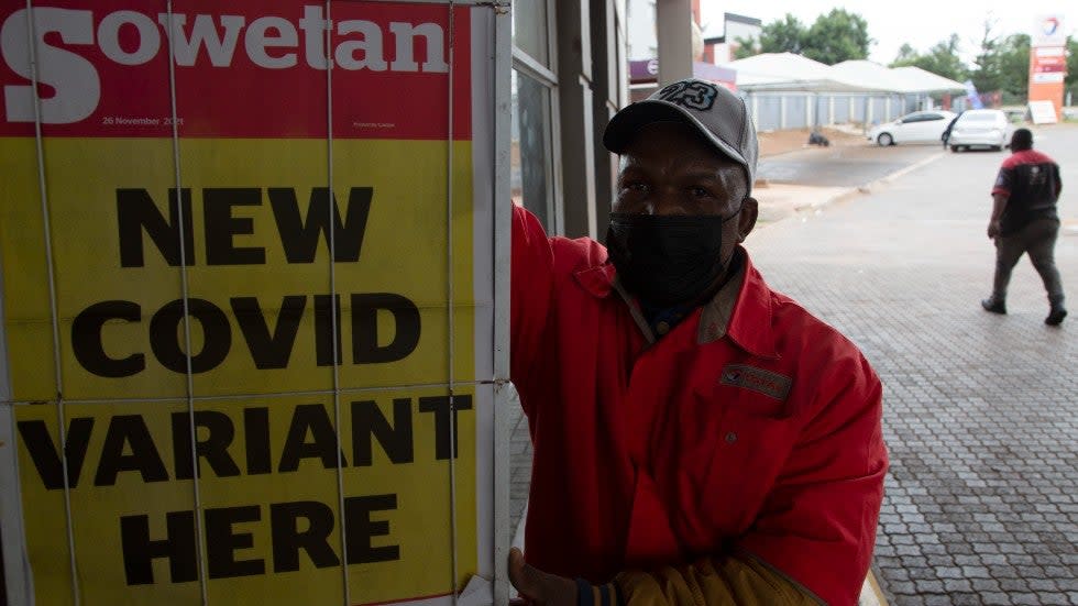 A petrol attendant stands next to a newspaper headline in Pretoria, South Africa