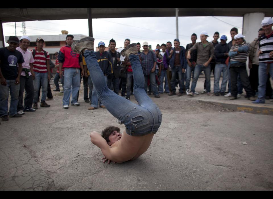 In this May 17, 2012 photo, Mexican street artist Ezer Alvarado performs in front of migrants waiting for a north bound train, in Lecheria, on the outskirts of Mexico City. While the number of Mexicans heading to the U.S. has dropped dramatically, a surge of Central American migrants is making the 1,000-mile northbound journey this year, fueled in large part by the rising violence brought by the spread of Mexican drug cartels. (AP Photo/Alexandre Meneghini)