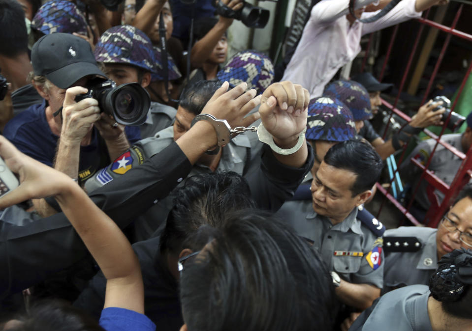 Members of Student Union and leaders of Peacock Generation "Thangyat" Performance Group, raise their hands with handcuffs upon arrival at a township court for their trial Wednesday, Oct. 30, 2019, in Yangon, Myanmar. Five member s of the Student Union received one year of hard labor after a satirical production against the military in April. (AP Photo/Thein Zaw)