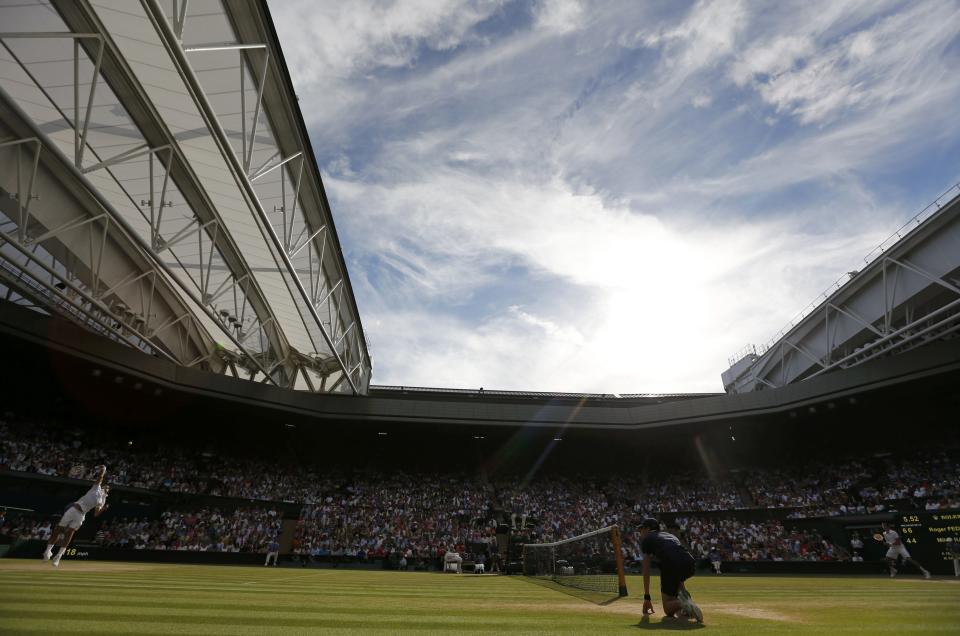 Roger Federer of Switzerland (L) serves during his men's singles semi-final tennis match against Milos Raonic of Canada at the Wimbledon Tennis Championships, in London July 4, 2014. REUTERS/Stefan Wermuth (BRITAIN - Tags: SPORT TENNIS)