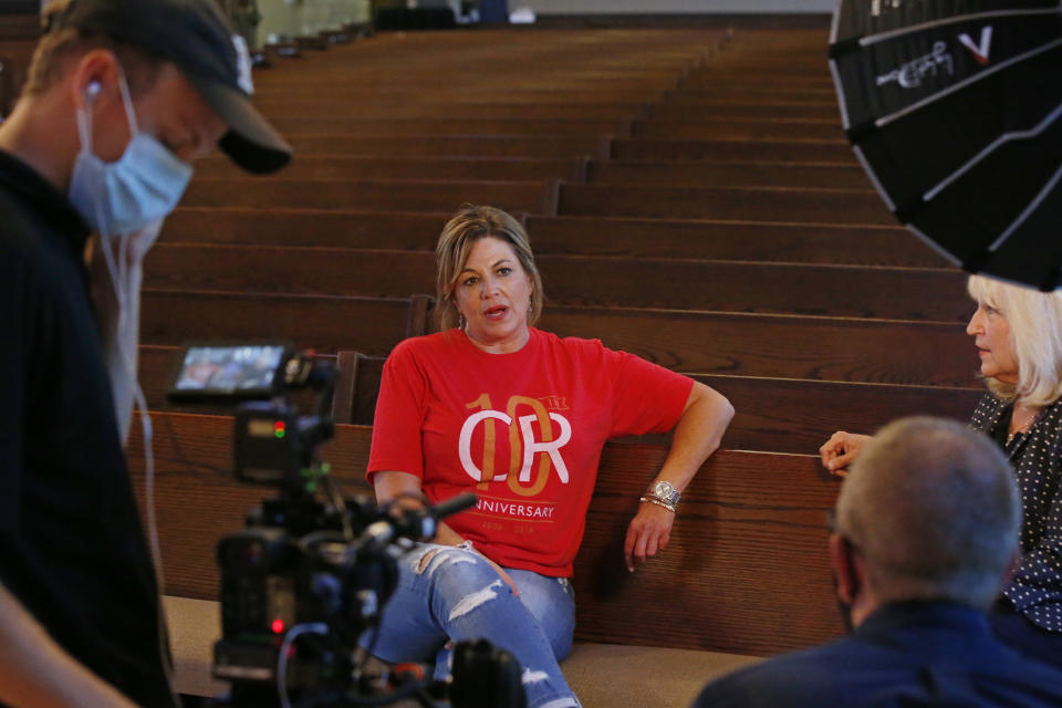 Teresa Stanfield, seated at center, the Oklahoma field director with Virginia-based Prison Fellowship, and Teresa Peden, seated right, pastor of recovery ministry at Crossing Community Church, talk with Drew Darby, left, and Topher Hall, foreground right, during a videotaping, Tuesday, Aug. 11, 2020, in Oklahoma City. Normally, Stanfield is behind bars, talking with inmates about how she changed the course of her troubled life. The coronavirus has forced her out of prisons. For the time being, Stanfield is videotaping her message. (AP Photo/Sue Ogrocki)