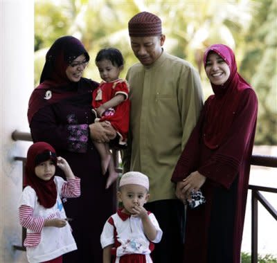 Ishak Md Nor, 40, is surrounded by his wives, Aishah Abdul Ghafar, left, 40, and Afiratul Abidah Mohd Hanan, 25, who are members of the newly launched Obedient Wives Club in Malaysia. (AP Photo)
