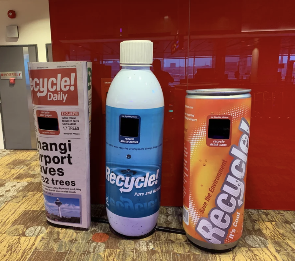 Recycling bins designed as a newspaper, water bottle, and soda can, promoting recycling in a creative way