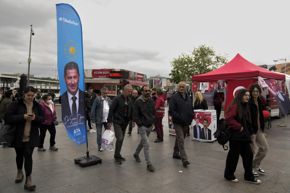 People walk past a banner of ATA alliance presidential candidate Sinan Ogan in Istanbul, Turkey, Thursday, May 11, 2023. Turkey is heading toward presidential and parliamentary elections on Sunday May 14, 2023. (AP Photo/Khalil Hamra)