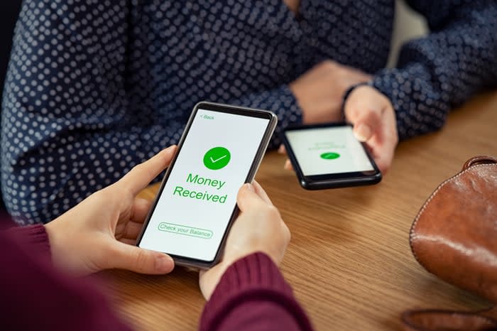 Two people using their smartphones to complete a peer-to-peer digital payment. 