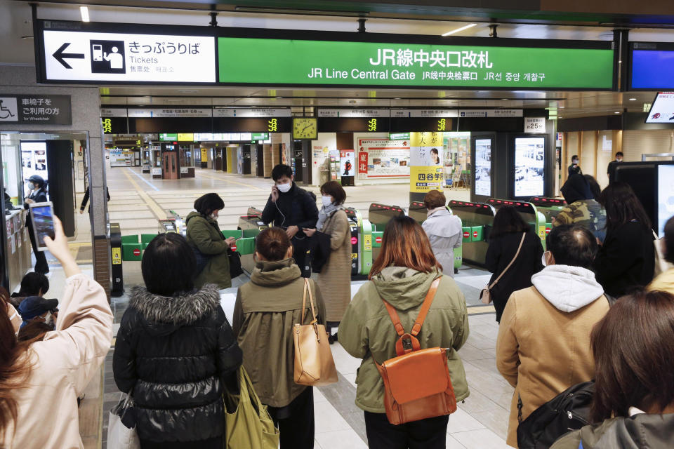 People gather in front of a ticket gate at a station as train services are suspended following an earthquake in Sendai, Miyagi prefecture, Japan Saturday, March 20, 2021. A strong earthquake struck Saturday off northern Japan, shaking buildings even in Tokyo and triggering a tsunami advisory for a part of the northern coast. (Kyodo News via AP)