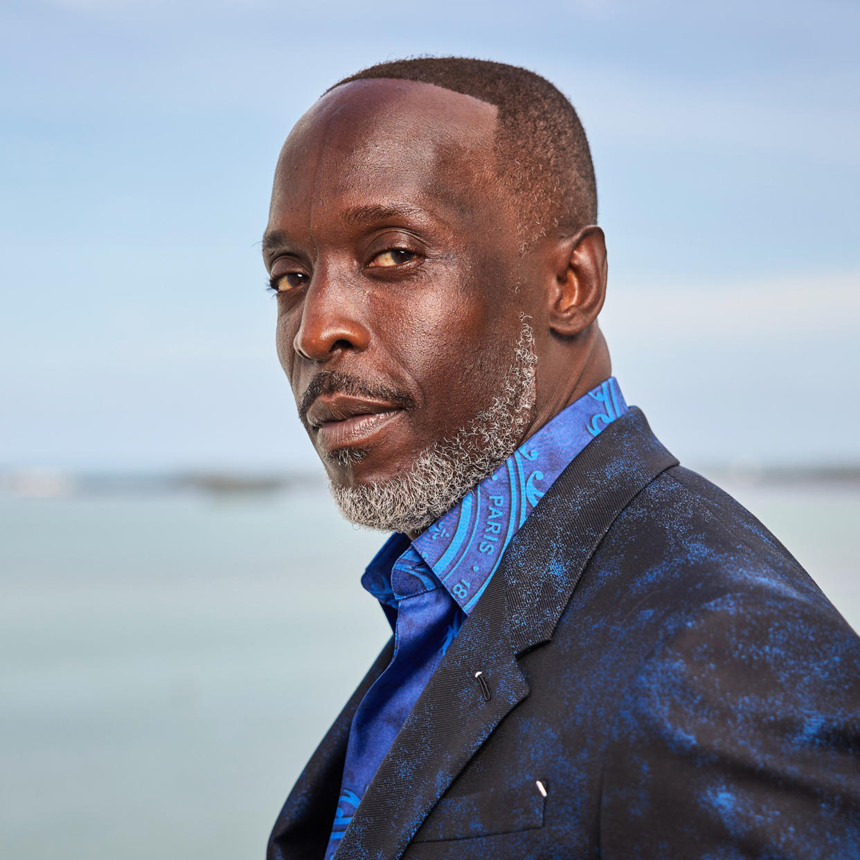 a close shot on Michael K. Williams who is looking at the camera over his shoulder in a blue button down shirt and black suit coat (Rodrigo Varela / Getty Images)