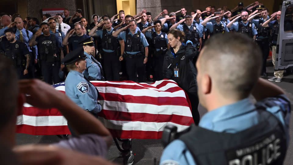 Law enforcement officers salute the flag-draped remains of fallen Minneapolis police Officer Jamal Mitchell as he is escorted to a waiting medical examiner's vehicle outside Hennepin County Medical Center in Minneapolis on Thursday. - Aaron Lavinsky/Star Tribune/AP