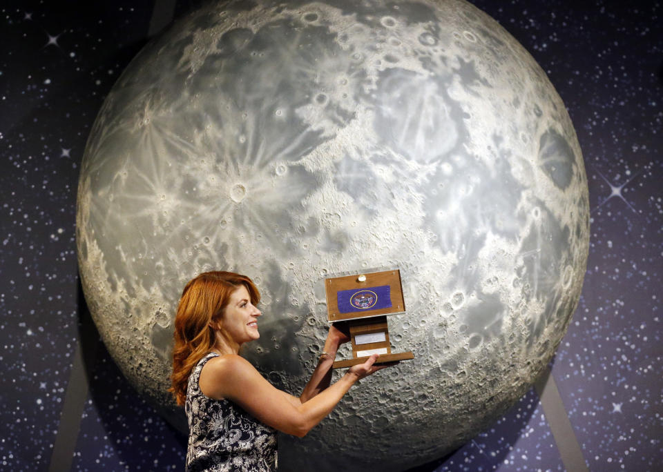 In this Thursday, Aug. 23, 2018, photo, Lindsie Smith, from the Clark Planetarium, holds moon rocks encased in acrylic and mounted on a wooden plaque at the Clark Planetarium, in Salt Lake City. A former NASA investigator who has spent more than a decade tracking missing moon rocks is closing in on his goal of finding all 50 lunar samples gifted to U.S. states after Neil Armstrong's first steps on the moon. In recent weeks, two more of the moon rocks that dropped off the radar after the 1969 Apollo 11 mission have been located in Louisiana and Utah. (AP Photo/Rick Bowmer)