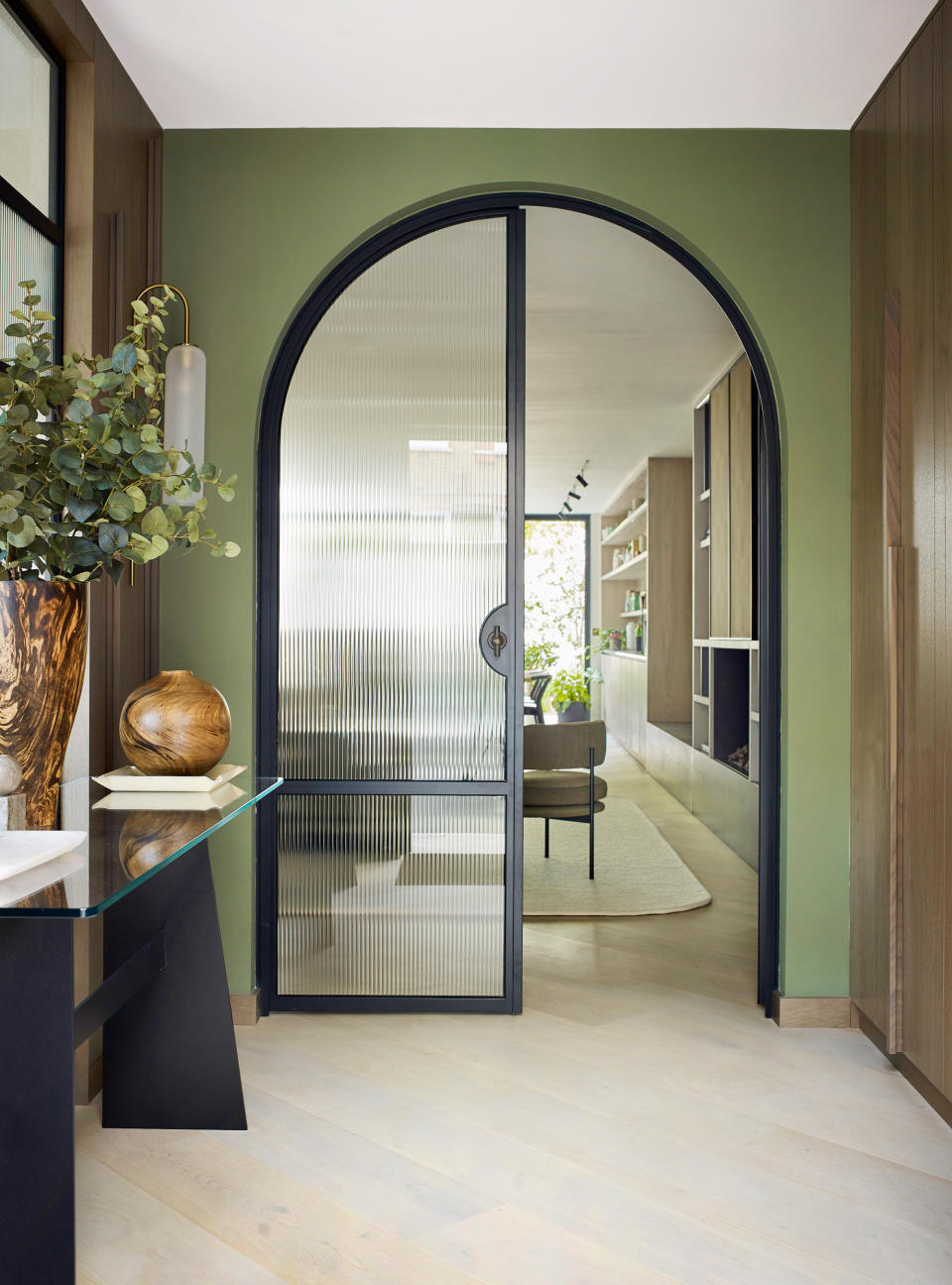 Green painted hallway with steel framed door and and wood floor