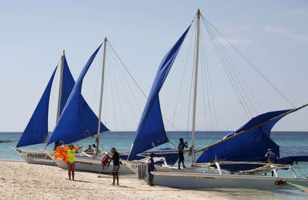 FILE PHOTO: Tourists takes photographs along local sailboats on the island of Boracay, central Philippines January 18, 2016. REUTERS/Charlie Saceda/File Photo