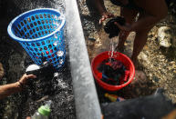 <p>A woman (R) washes clothes with water funneled from a mountain stream nearly one month after Hurricane Maria struck on Oct.19, 2017 in Utuado, Puerto Rico. Homes in the area have no running water or electricity. (Photo: Mario Tama/Getty Images) </p>