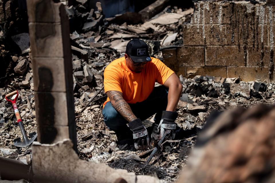 A father searches in the ruins of his home.