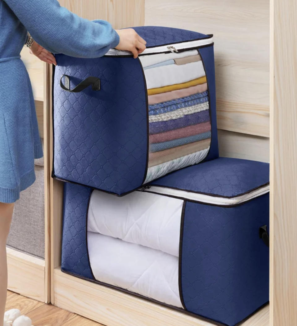 a person stacking two full linen storage bags in a closet