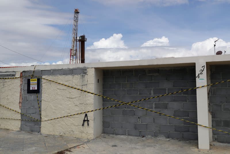 A condemned building sits in front of mining equipment used by the petrochemical company Braskem in Maceio