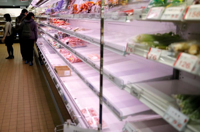 A shopper wearing a protective face mask, following an outbreak of the coronavirus disease (COVID-19), is seen next to empty shelves at a supermarket in Tokyo