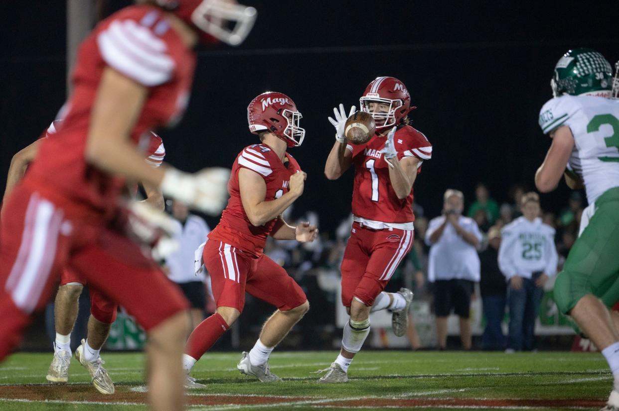 Colon senior Simon Vinson hands the ball off to senior Connor Hetman during a playoff game against Mendon at Colon High School on Friday, Nov. 4, 2022.