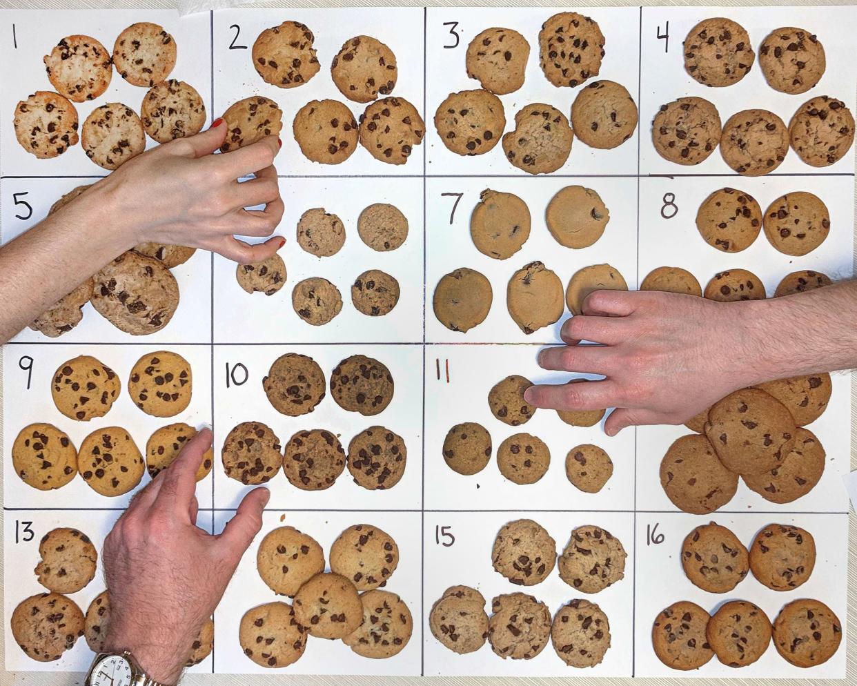 chocolate chip cookies laid out and numbered on posterboard, hands reaching for cookies